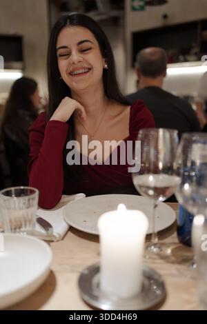 Jeune femme aux accolades souriantes profitant d'un moment convivial dans un restaurant chic Banque D'Images