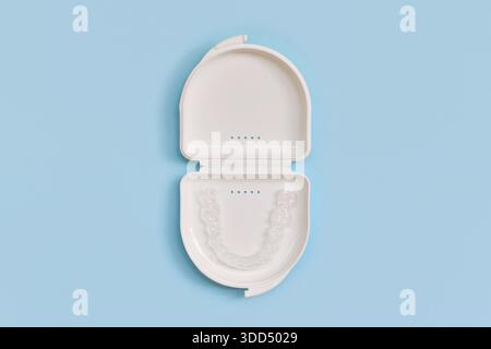 Protège-dents dentaires transparents personnalisés aligners clairs pour la mâchoire inférieure dans un boîtier blanc sur fond bleu Banque D'Images