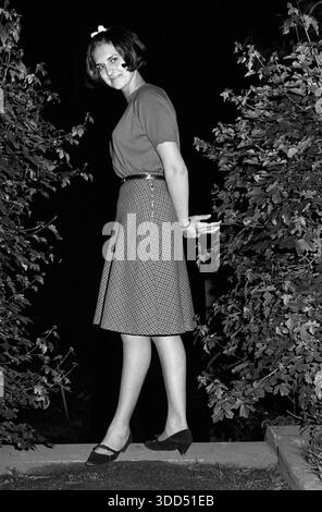 Années soixante, 28.05.1966, Allemagne, personnes, femmes, fille 17 à 20 ans, prise de vue photo dans un jardin la nuit, pull et jupe, cheveux de longueur moyenne, portrait en longueur, vue de côté, debout, bras dans le dos, souriant, Angelika Banque D'Images