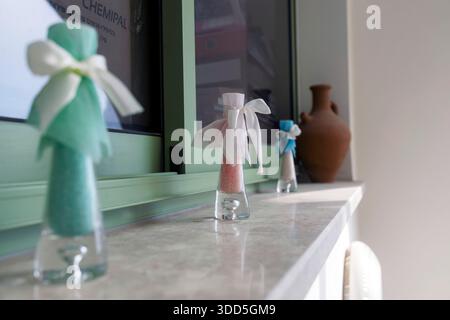 Petites bouteilles souvenir en verre remplies de sable coloré ou de liquide et enveloppées dans du tulle avec des rubans, assis sur un rebord de fenêtre. Banque D'Images