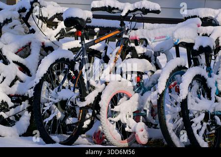Un groupe de bicyclettes entreposées dans un rack extérieur et recouvertes de neige fraîche dans les régions rurales de l'Alberta au Canada Banque D'Images