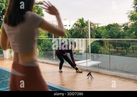 Femme faisant de l'exercice en plein air, créant une vidéo de fitness avec smartphone sur un trépied Banque D'Images