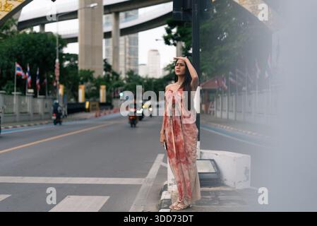 Femme protégeant les yeux du soleil sur la rue de la ville à la recherche de la direction Banque D'Images