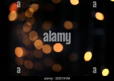Lumières bokeh dorées chaudes éclairant un fond abstrait sombre avec espace de copie Banque D'Images