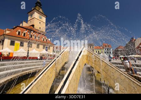 Les gens apprécient l'atmosphère vibrante du marché sur la place du Conseil, Brasov, Transylvanie, Roumanie avec l'ancien hôtel de ville et sa tour de l'horloge en arrière-plan Banque D'Images