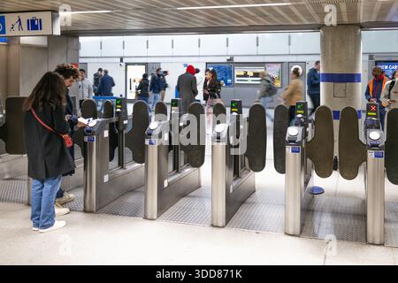 Entrée de la station de métro très fréquentée avec des navetteurs passant des barrières automatisées. Londres, Royaume-Uni, 25 février 2024 Banque D'Images