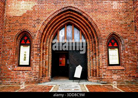Kaliningrad, Russie - 01 mai 2013 - entrée d'église gothique en brique voûtée avec porte en bois et fenêtres rouges. Banque D'Images
