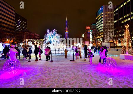 Sapporo, Hokkaido, Japon - 17 décembre 2025 : sculpture de neige illuminée de couleurs vives, avec la Tour de télévision Sapporo comme toile de fond dans Odori Park Wint Banque D'Images