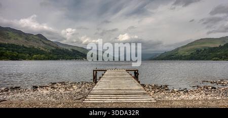 Une vue panoramique sur une petite jetée à travers Loch Earn en Écosse vers les collines lointaines Banque D'Images