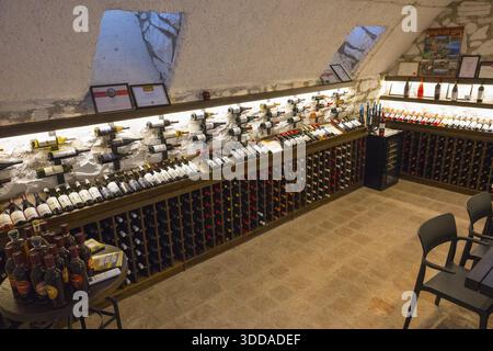 Cave à vin avec étagères illuminées pleines de bouteilles de vin et chaises simples et tables pour les dégustations, maison de vin géorgienne-allemande de 1915, Bolnissi, K. Banque D'Images