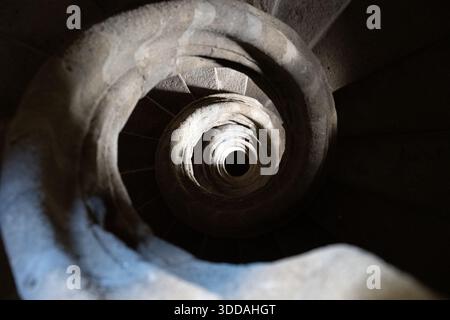 Un escalier en colimaçon vu d'en haut, présentant des pierres complexes et des ombres Banque D'Images