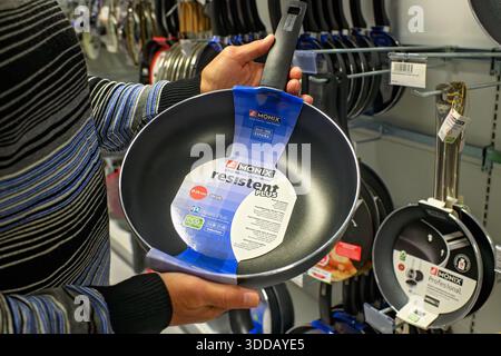 Sliema, Malte - 24 décembre 2025 : un homme tient un wok antiadhésif Monix Resistent plus, vérifiant l'étiquette et la qualité dans un magasin d'ustensiles de cuisine. Banque D'Images