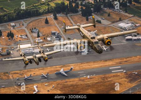 Un bombardier nord-américain B-25 Mitchell et un Lockheed P-38L Lightning volent ensemble en formation lors du salon aéronautique international d'Abbotsford au Canada en 2025. Le B-25, immatriculé N8195H et marqué Army Air Forces Serial 43-0748 avec le nez art 'Heavenly Body', est accompagné du P-38L Lightning immatriculé N2114L avec les numéros de code NX2114L, 427083 et 5781. Le P-38 présente des flèches jumelles distinctives et un accent visible de couleur mandarine, mettant en évidence deux avions restaurés de la seconde Guerre mondiale en vol coordonné. Banque D'Images