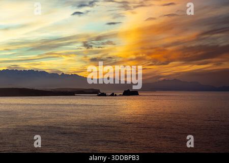 Coucher de soleil à couper le souffle sur la côte de Liencres en Cantabrie, au nord de l'Espagne, avec les sommets des montagnes Picos de Europa au loin sous les nuages dorés Banque D'Images