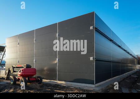 Extérieur d'entrepôt industriel moderne avec mur de panneau sandwich gris installé sous ciel bleu Banque D'Images