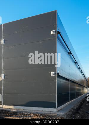 Mur extérieur de bâtiment industriel avec des panneaux sandwich sombres modernes sous le ciel bleu Banque D'Images