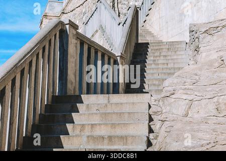 Escaliers extérieurs en béton montant, avec une forte lumière du soleil projetant des ombres géométriques sur les marches et les balustrades, montrant la conception de l'architecture Banque D'Images