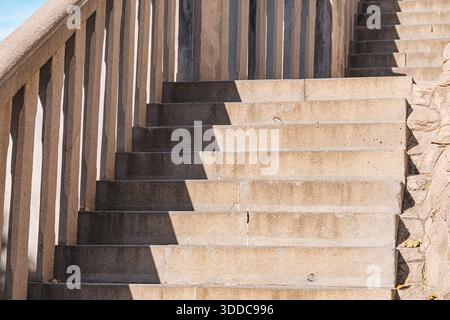 Escaliers extérieurs en béton montant, avec une forte lumière du soleil projetant des ombres géométriques sur les marches et les balustrades, montrant la conception de l'architecture Banque D'Images