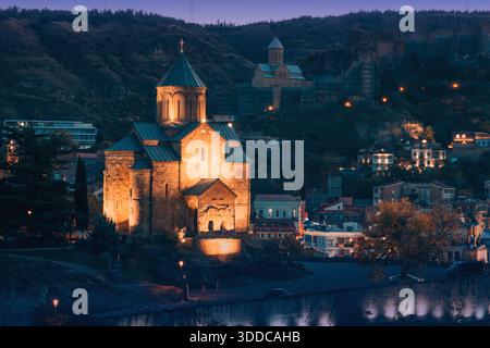 31 octobre 2025, Tbilissi, Géorgie : église Metekhi éclairée, surplombant la rivière Mtkvari et l'architecture de la vieille ville de Tbilissi avec des collines Banque D'Images