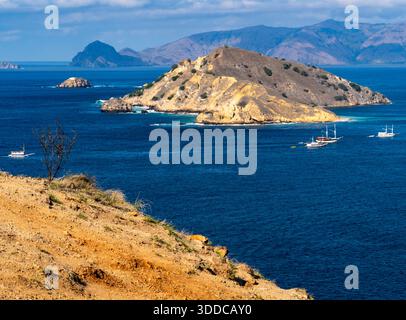 Vue panoramique d'une île rocheuse entourée par l'océan bleu avec des bateaux. Banque D'Images