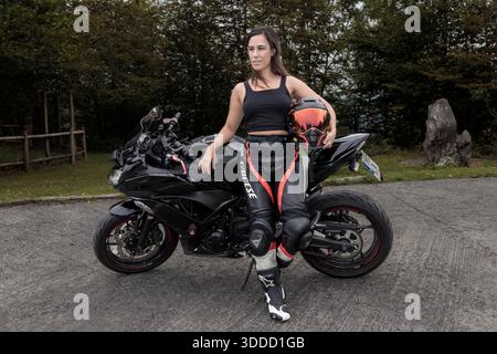 Femme debout à côté de sa moto, se reposant après une promenade sur une route extérieure Banque D'Images