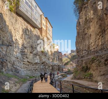 3 novembre 2025, Tbilissi, Géorgie : les gens marchent le long d'une promenade en bois dans le canyon de Leghvtakhevi, avec des maisons à flanc de falaise surplombant la gorge étroite Banque D'Images