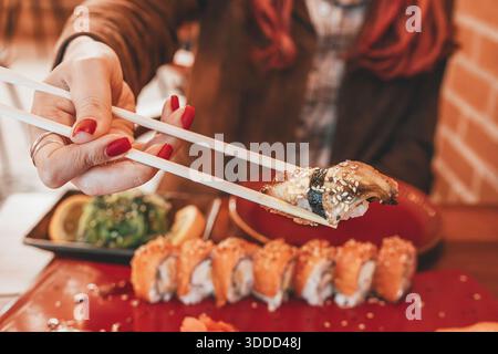 Femme se sentant heureuse tout en mangeant de délicieux sushis et salade de wakame Banque D'Images