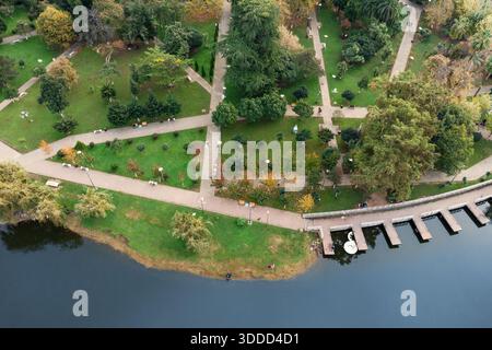 Parc de la ville offrant une retraite paisible, avec des espaces verts luxuriants, des arbres divers, des chemins sinueux, et un lac calme avec une jetée Banque D'Images