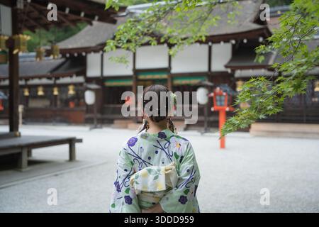 Femme portant le yukata debout devant les bâtiments historiques en bois du sanctuaire Kawai. Kyoto, Japon. Banque D'Images