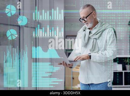 Double exposition de la science des données mature travaillant avec un ordinateur portable dans le bureau et un écran virtuel avec des statistiques Banque D'Images