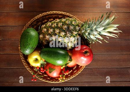 Vue de dessus d'un panier tissé rempli d'ananas, d'avocats et de pommes Banque D'Images