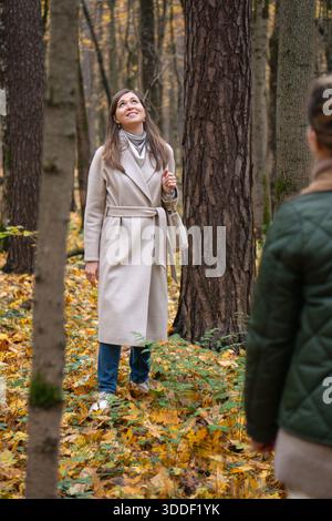 Femme marchant dans la forêt d'automne dans le parc Timiryazevsky, Moscou, entourée de feuilles d'or, de grands arbres, regardant vers le haut avec une expression calme et réfléchie Banque D'Images