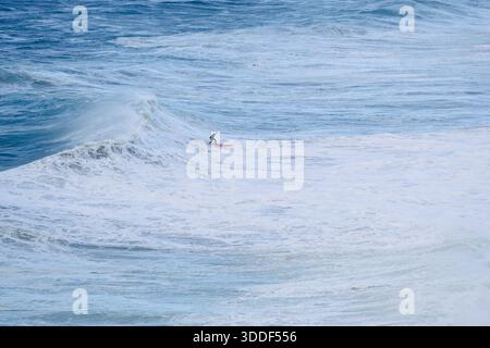 Surfeur chevauchant une grande vague océanique par une journée lumineuse, en équilibre sur une planche de surf Banque D'Images