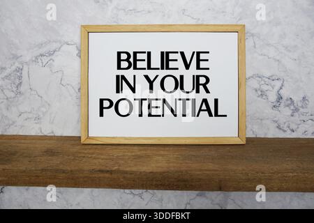 Croyez en votre texte potentiel écrit sur tableau blanc avec étagère en bois et fond de marbre Banque D'Images
