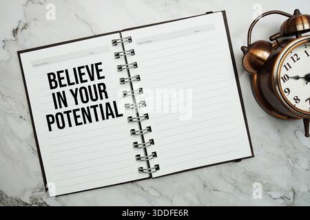 Croyez en votre texte potentiel écrit sur bloc-notes avec réveil Banque D'Images
