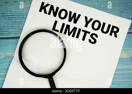 Connaître vos limites texte écrit sur bloc-notes avec loupe plate sur fond en bois Banque D'Images