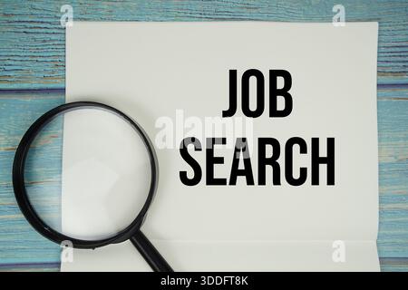 Texte de recherche d'emploi écrit sur le bloc-notes avec la loupe plate sur fond en bois Banque D'Images
