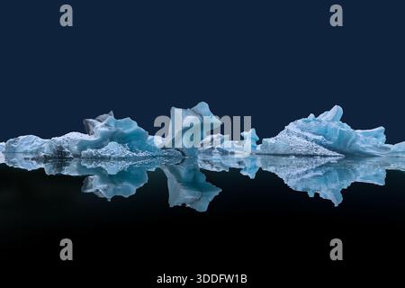 Blocs de glace flottants sur la surface de l'eau avec des reflets sur fond bleu foncé dans la lagune de Jokulsarlon, Islande - espace copie Banque D'Images