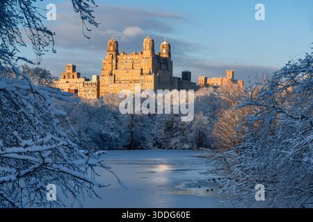 New York City vue hivernale sur le lac gelé Central Park, avec des arbres enneigés. Les bâtiments de l'Upper West Side captent la lumière du coucher du soleil Banque D'Images