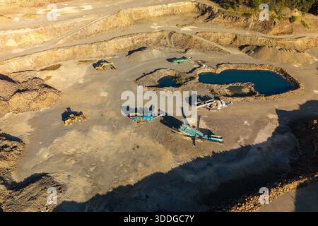 Une vaste carrière à ciel ouvert est vue d'en haut, avec des excavatrices, des concasseurs et de grands stocks de matières premières extraites. Banque D'Images