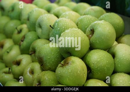 Gros plan de pommes vertes fraîchement lavées recouvertes de gouttelettes d'eau, bien emballées et scintillantes avec fraîcheur et couleur vibrante. Banque D'Images