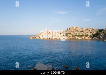 Des roches de granit baignées de soleil forment un promontoire côtier spectaculaire à Capo Testa, en Sardaigne, s'élevant au-dessus des eaux bleues calmes de la Méditerranée sous un ciel clair. Banque D'Images