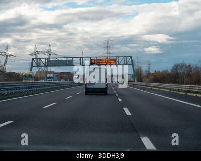 Véhicules circulant sur une autoroute avec un panneau d'affichage électronique affichant des informations aux conducteurs par temps nuageux. Vicence, Italie - 21 novembre 2025 Banque D'Images