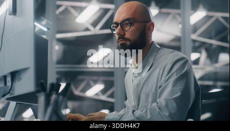 Spécialiste INFORMATIQUE masculin barbu avec lunettes, intensément concentré sur l'écran d'ordinateur. Caractéristiques d'arrière-plan Cool, environnement technique de la salle de contrôle du serveur. Analyse des données critiques et expertise dédiée. Banque D'Images