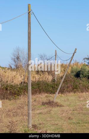 L'un des poteaux en bois d'une vieille ligne électrique a été dangereusement incliné par le mauvais temps dans la campagne, Fauglia, Pise, Italie Banque D'Images