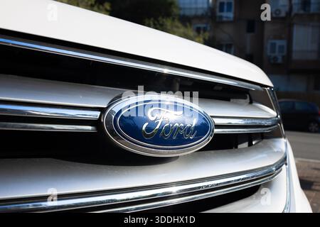 Gros plan de l'emblème Ford bleu sur la calandre argentée d'une voiture blanche, Givatayim, Israël, 4 décembre 2025 Banque D'Images