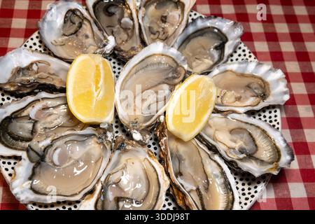 Huîtres fraîches sur le marché hebdomadaire français, nourriture de rue, portion d'huîtres ouvertes avec citron, fruits de mer, France, gros plan Banque D'Images
