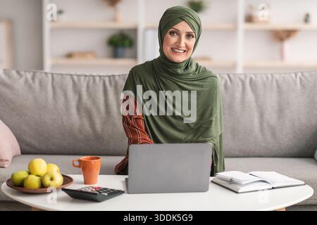 Happy mature Daech Lady utilisant un ordinateur portable souriant assis à la maison Banque D'Images