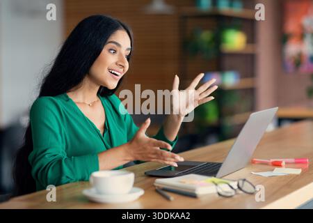 Femme émotive du Moyen-Orient ayant des conversations vidéo avec des collègues Banque D'Images
