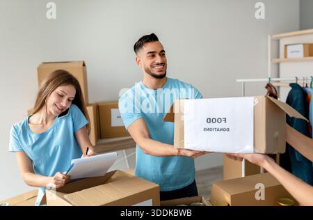 Happy Volunteers emballez des dons alimentaires tout en coordonnant des projets dans le bureau des organisations caritatives Banque D'Images